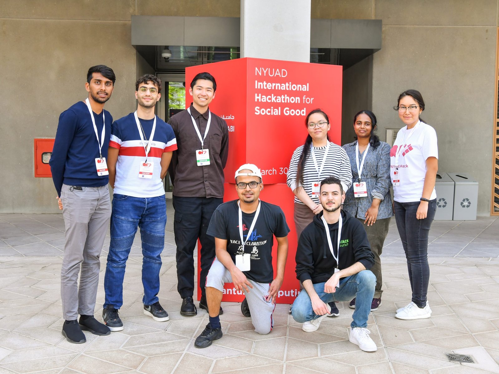 The qSa’id team in front of the NYUAD International Hackathon for Social Good sign.